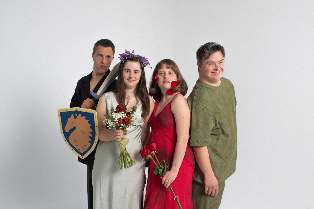 Teatre Sense Límits-EÒLIA CSAD Quatre persones posen per a una foto amb vestits de caràcter i objectes simbòlics sobre un fons blanc.