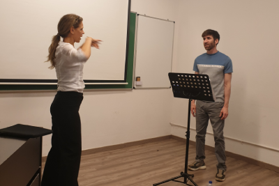 Masterclass Cristina Baggio-EÒLIA CSAD-2026 Una professora amb camisa blanca i pantalons negres gesticula amb energia davant d'un alumne durant una masterclass.